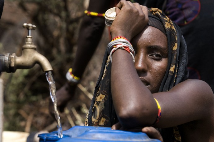 A Gabbra woman looks on as the water fills his can